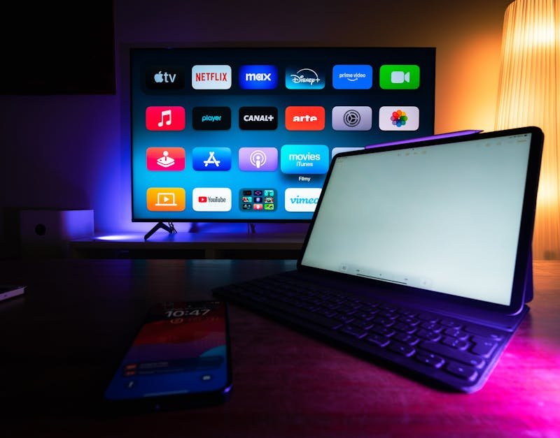 Smart TV displaying streaming app icons, tablet with keyboard in foreground, and smartphone showing time, illustrating modern tech integration for lifestyle upgrades.