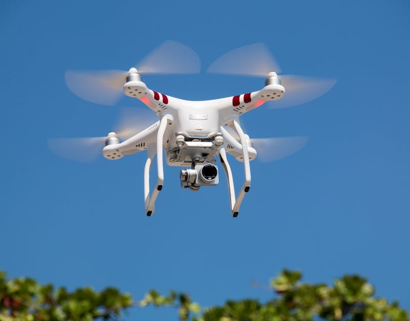 Drone flying against a clear blue sky, showcasing advanced technology relevant to smart home security devices.