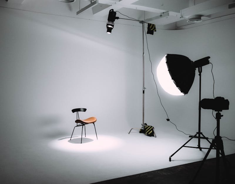 Studio setup featuring a spotlight on a chair, with photography equipment including a softbox and lighting rig, ideal for camera product reviews and content creation.