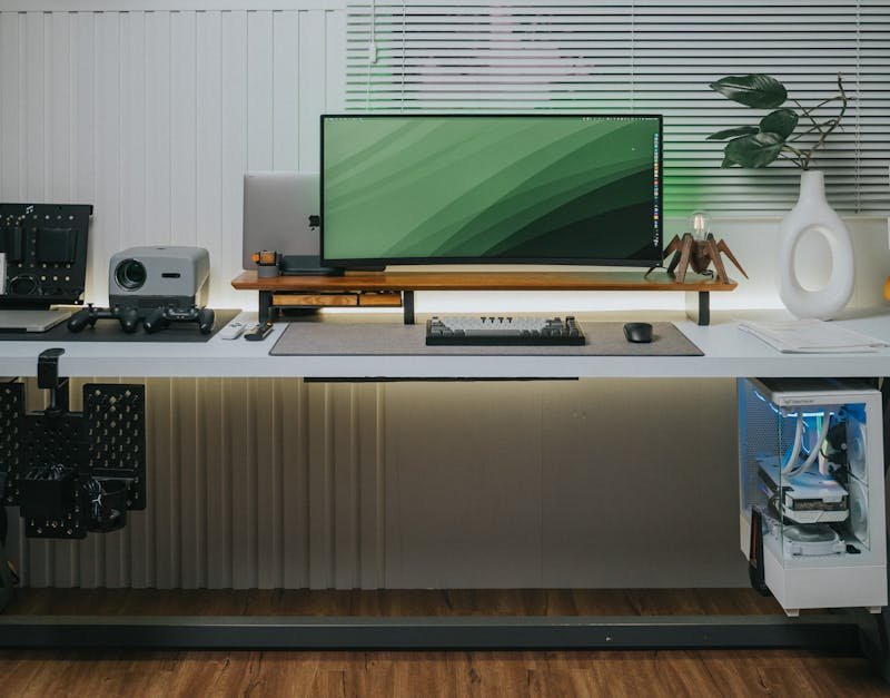 Modern ergonomic gaming desk setup with a large green monitor, gaming accessories, and a stylish plant, highlighting high-tech solutions for gamers in 2025.