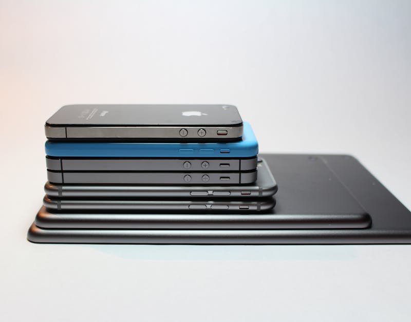 Stack of various smartphones and tablets in different colors and sizes, showcasing modern gadget design and technology.