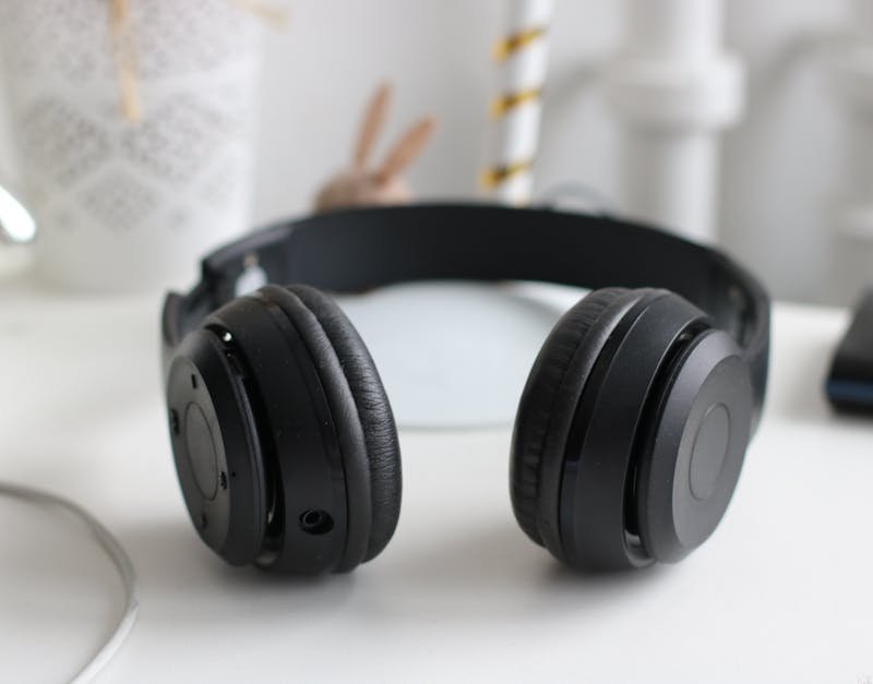 Black over-ear headphones on a desk, highlighting features relevant to noise-cancelling technology, surrounded by a minimalist workspace setting.