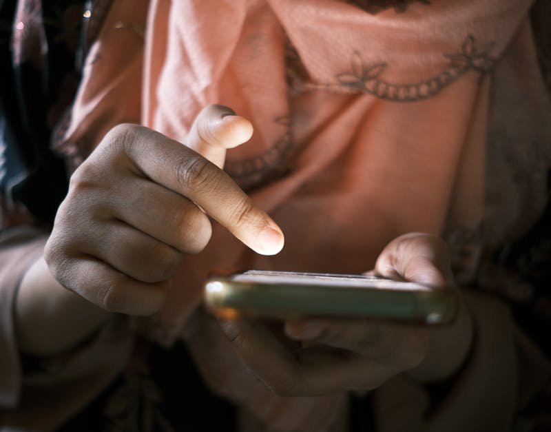 Close-up of hands using a smartphone indoors, highlighting touch technology.