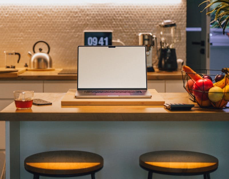 A contemporary kitchen island featuring a laptop, fruit bowl, and coffee setup, perfect for a home office.