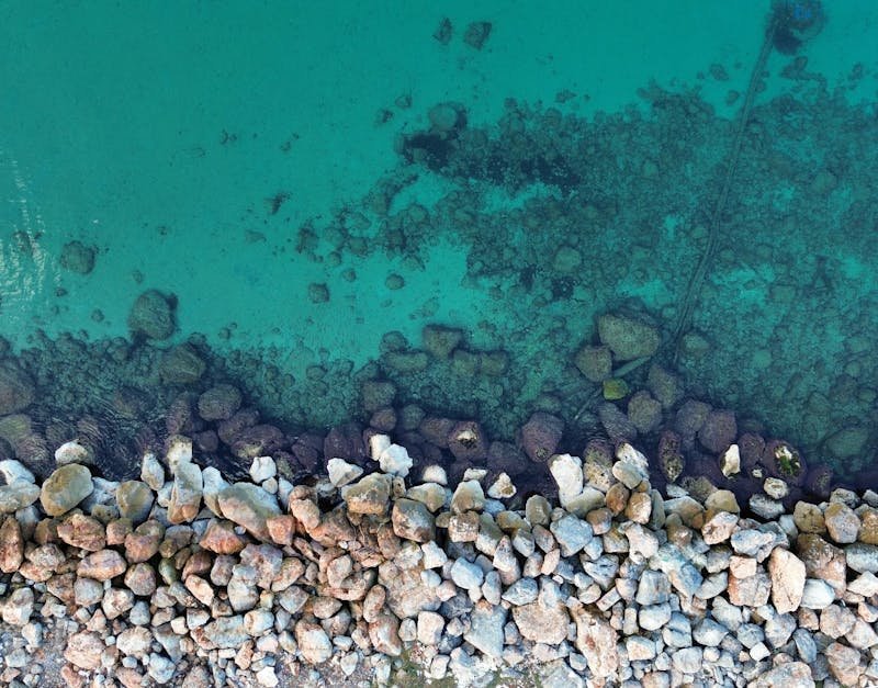 A stunning aerial view of rocks and clear turquoise sea water creating a perfect natural contrast.
