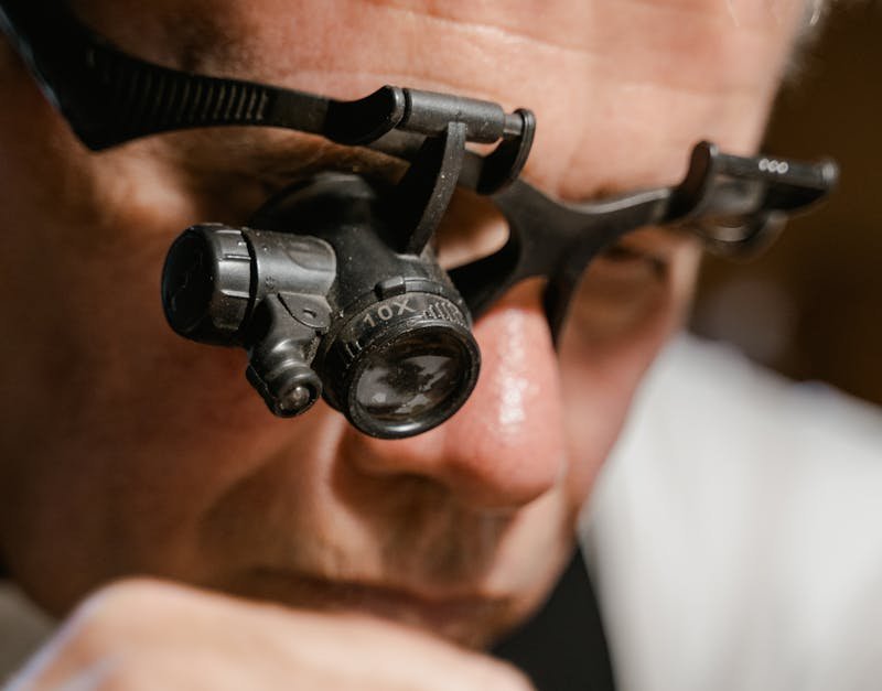 Detailed close-up of a watchmaker using a magnifying glass for precision work.