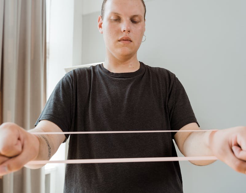 Man exercising with a resistance band indoors, promoting home fitness and wellness.