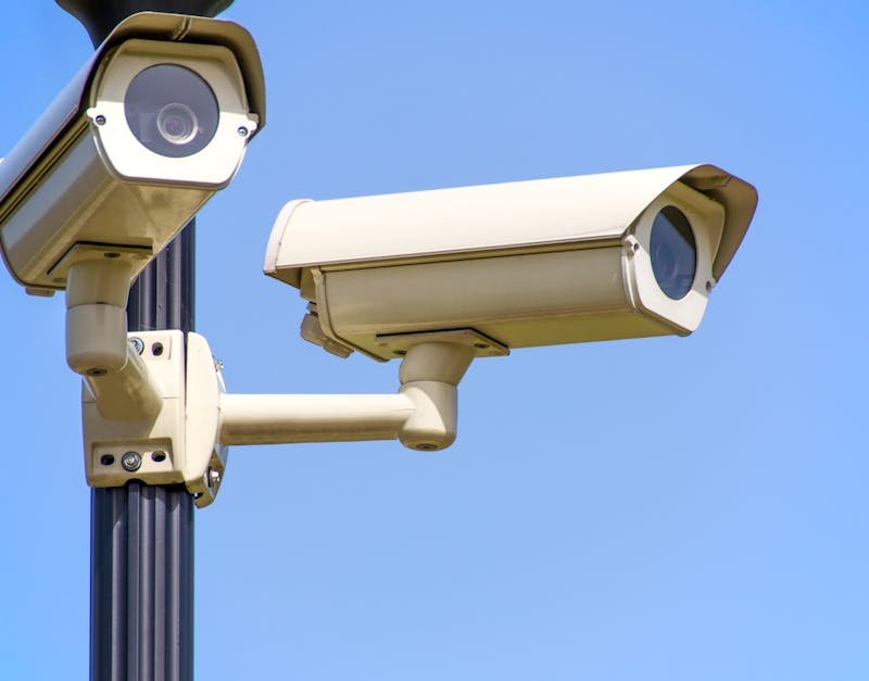 Outdoor security cameras mounted on a pole against a clear blue sky, ensuring vigilant surveillance.