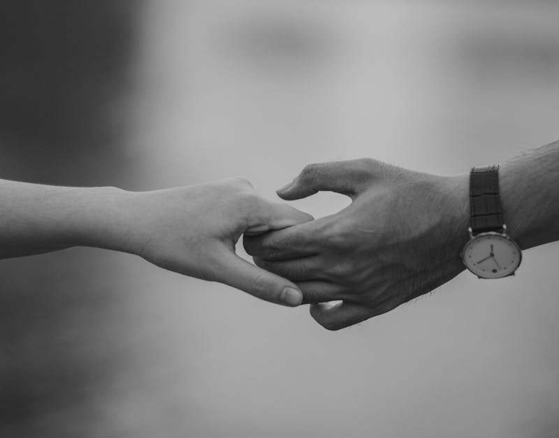 Monochrome image of two hands holding, symbolizing love and connection.
