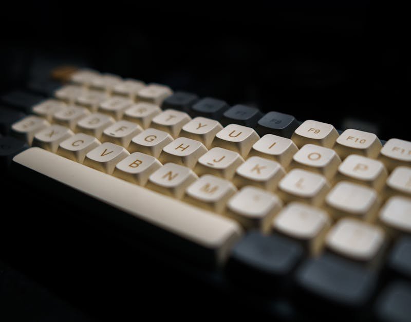 Close-up of a modern mechanical keyboard with white keycaps in a dark setting.